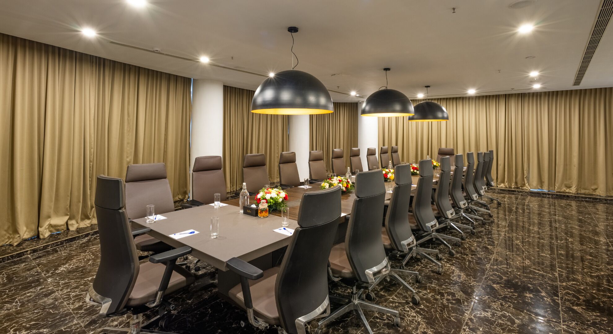 A conference room with a long table, chairs, and overhead lighting.