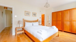 Quarto espaçoso com uma cama de madeira grande, um guarda-roupa de madeira e um candelabro.