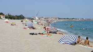 A beach with people sunbathing, umbrellas, and boats. - Beautiful River-front Villa with Natural Pool & Aircon (Sorède)
