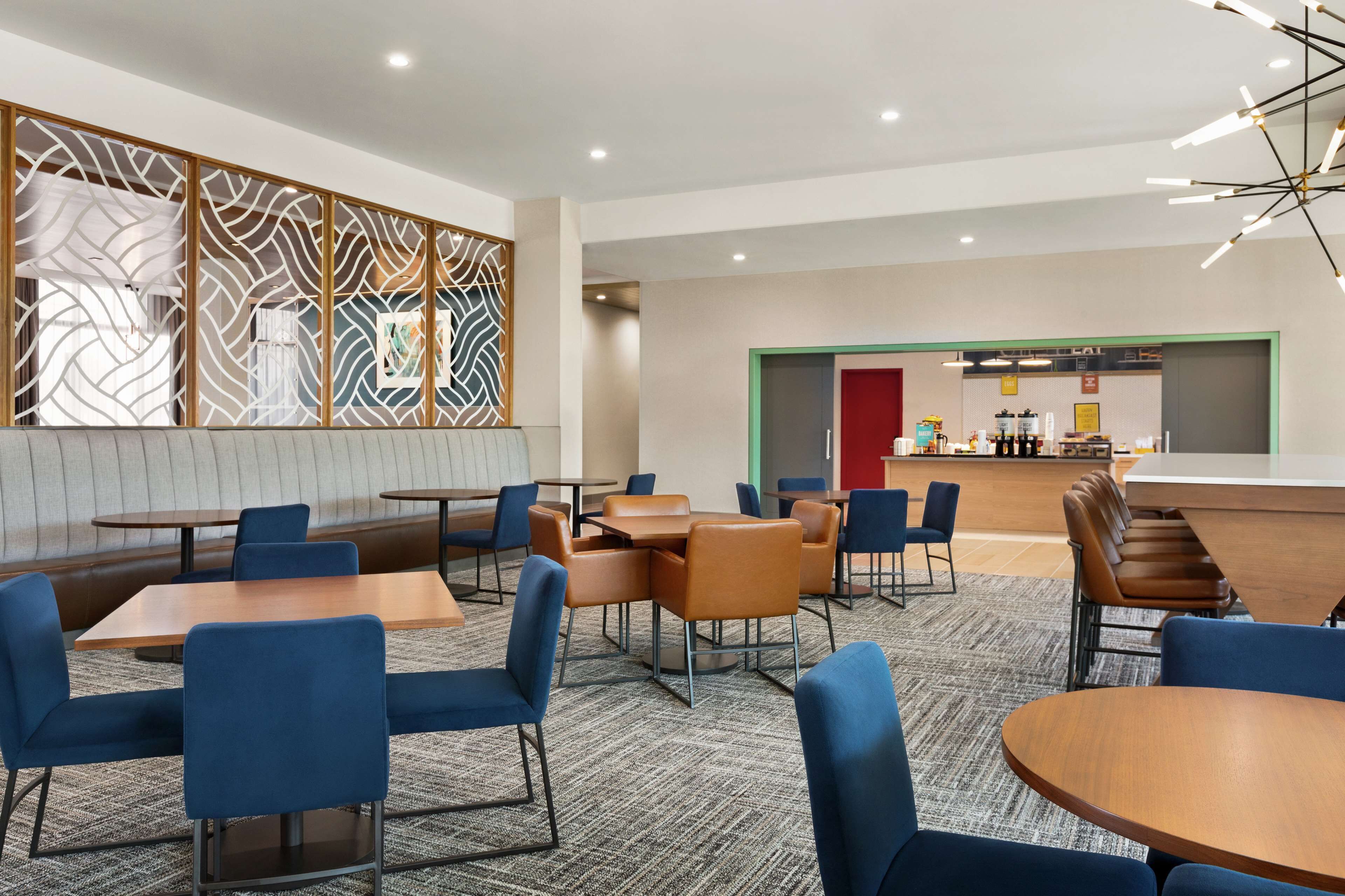 A modern hotel lobby with seating areas, a bar, and a reception desk.
