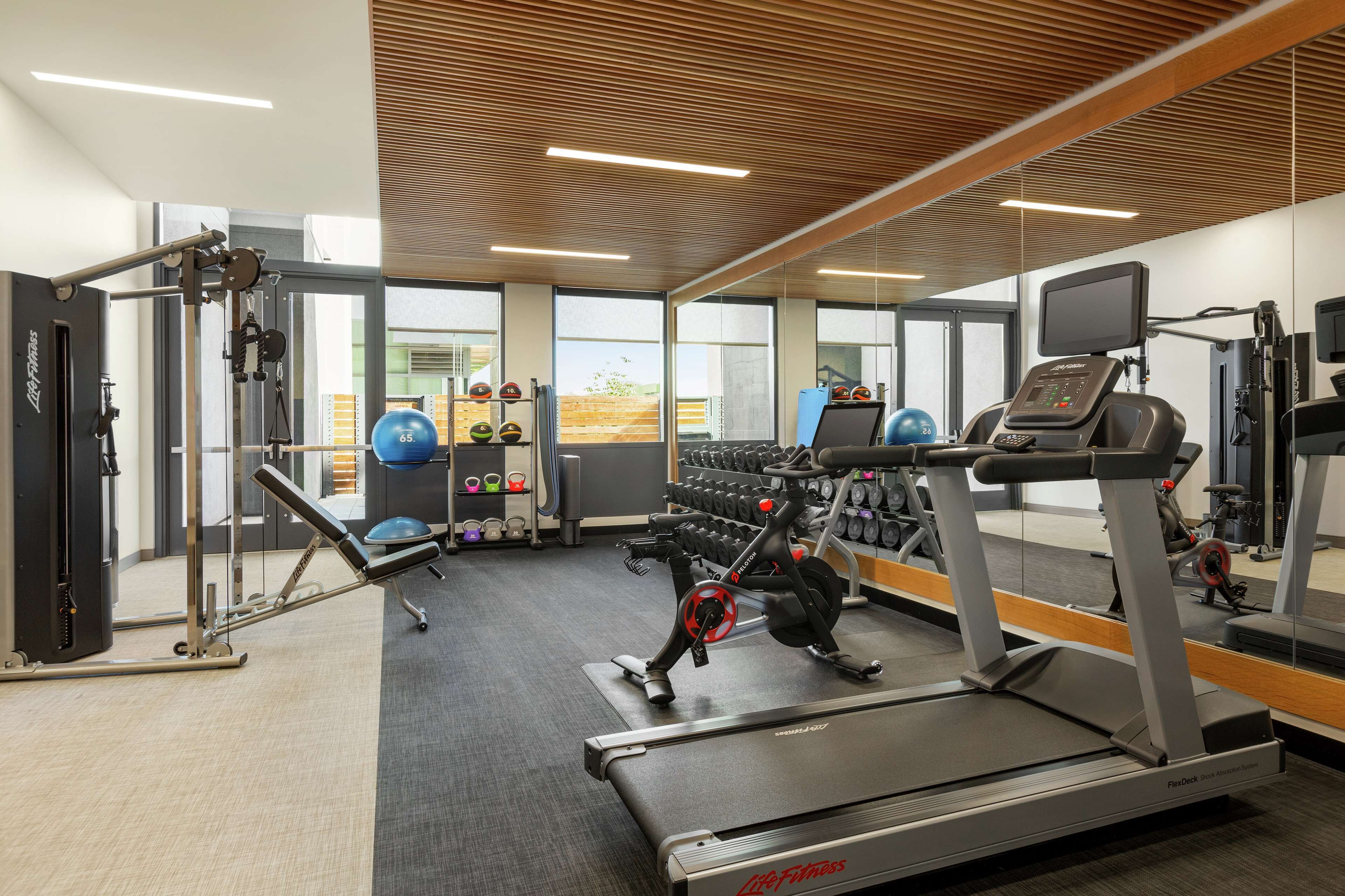 A gym with cardio equipment, weight machines, and dumbbells.