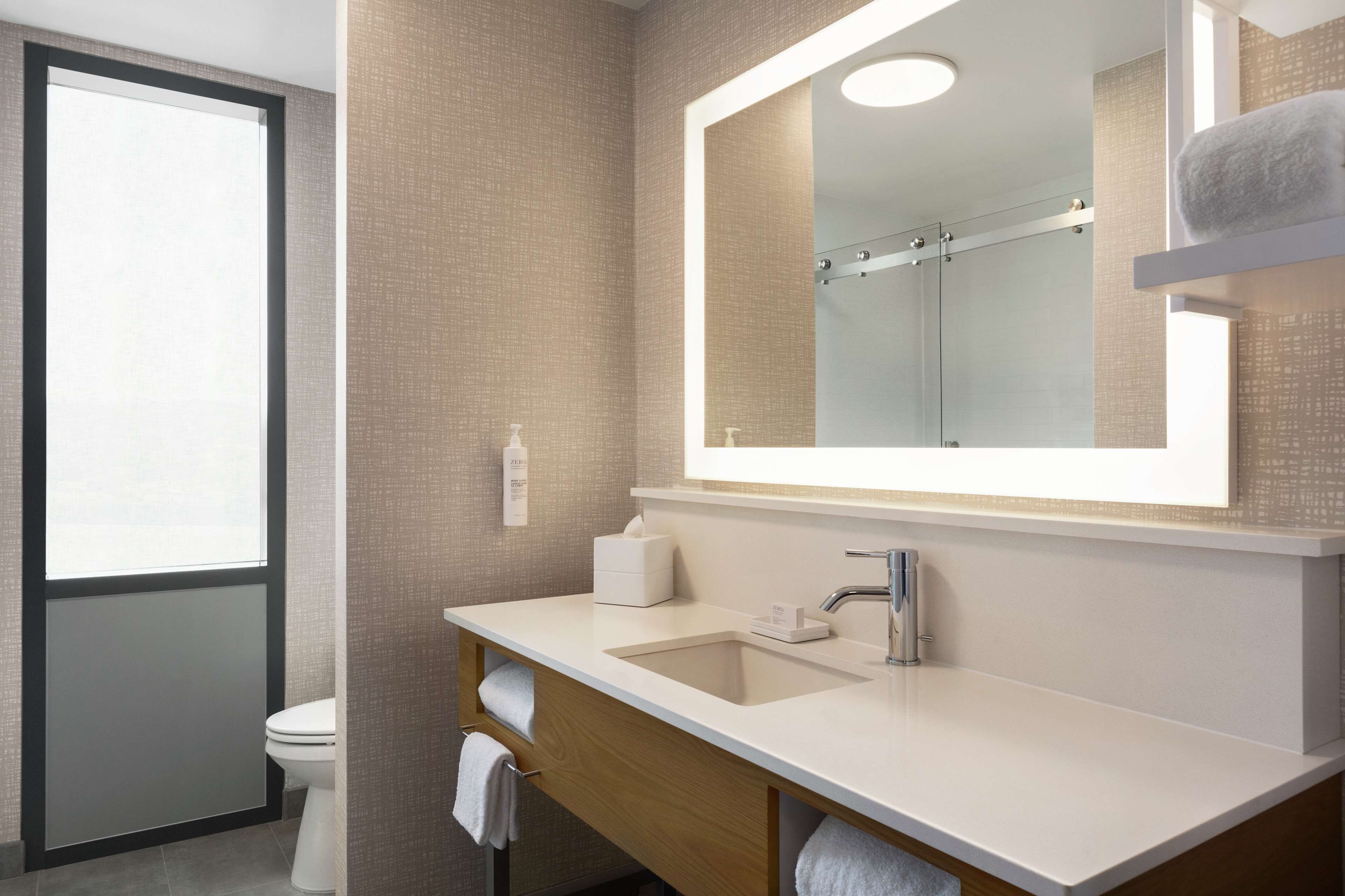 Un baño moderno con un espejo grande, un lavabo y un inodoro.