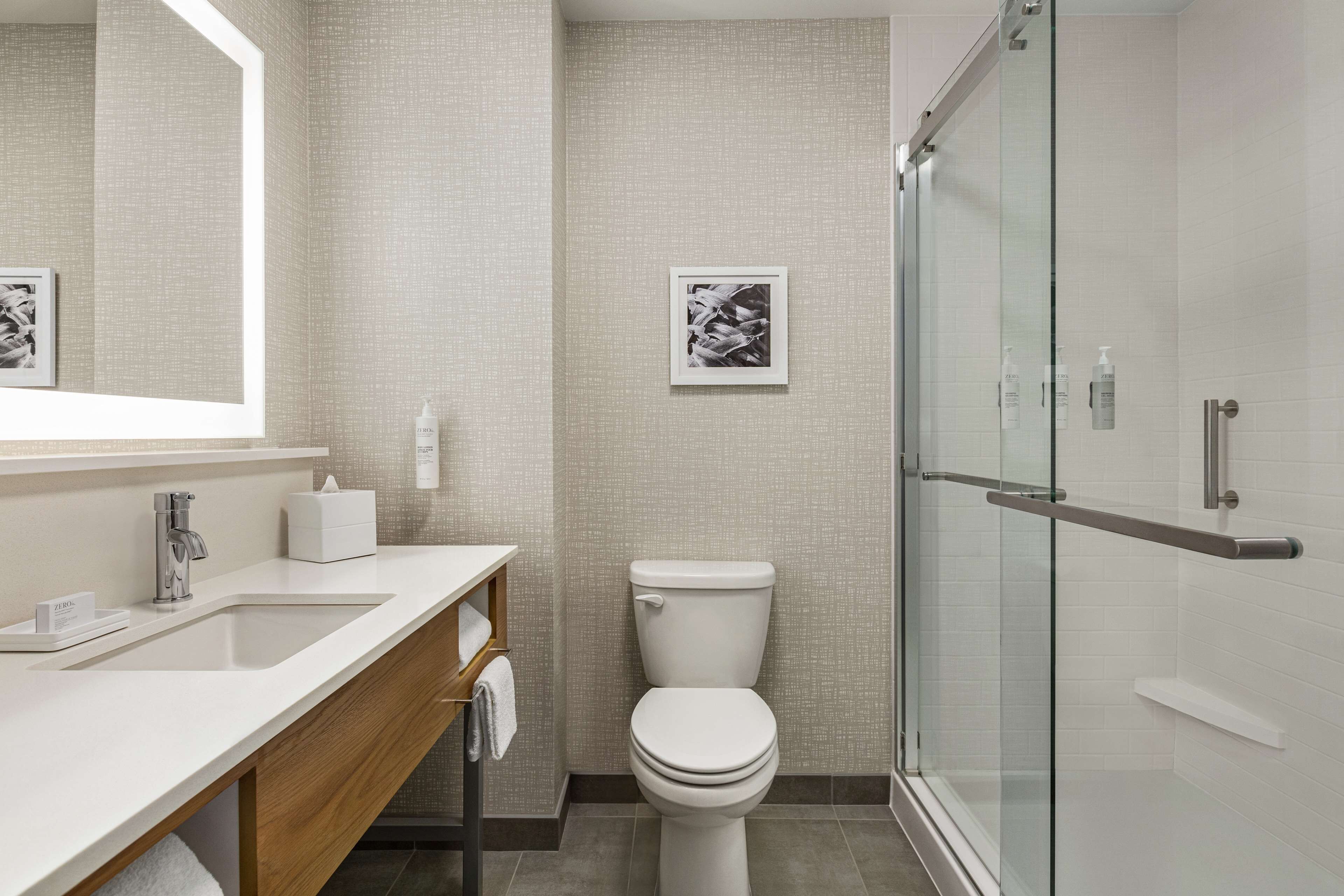 A modern bathroom with a white sink, a toilet, and a glass shower enclosure.