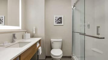 A modern bathroom with a white sink, a toilet, and a glass shower enclosure.