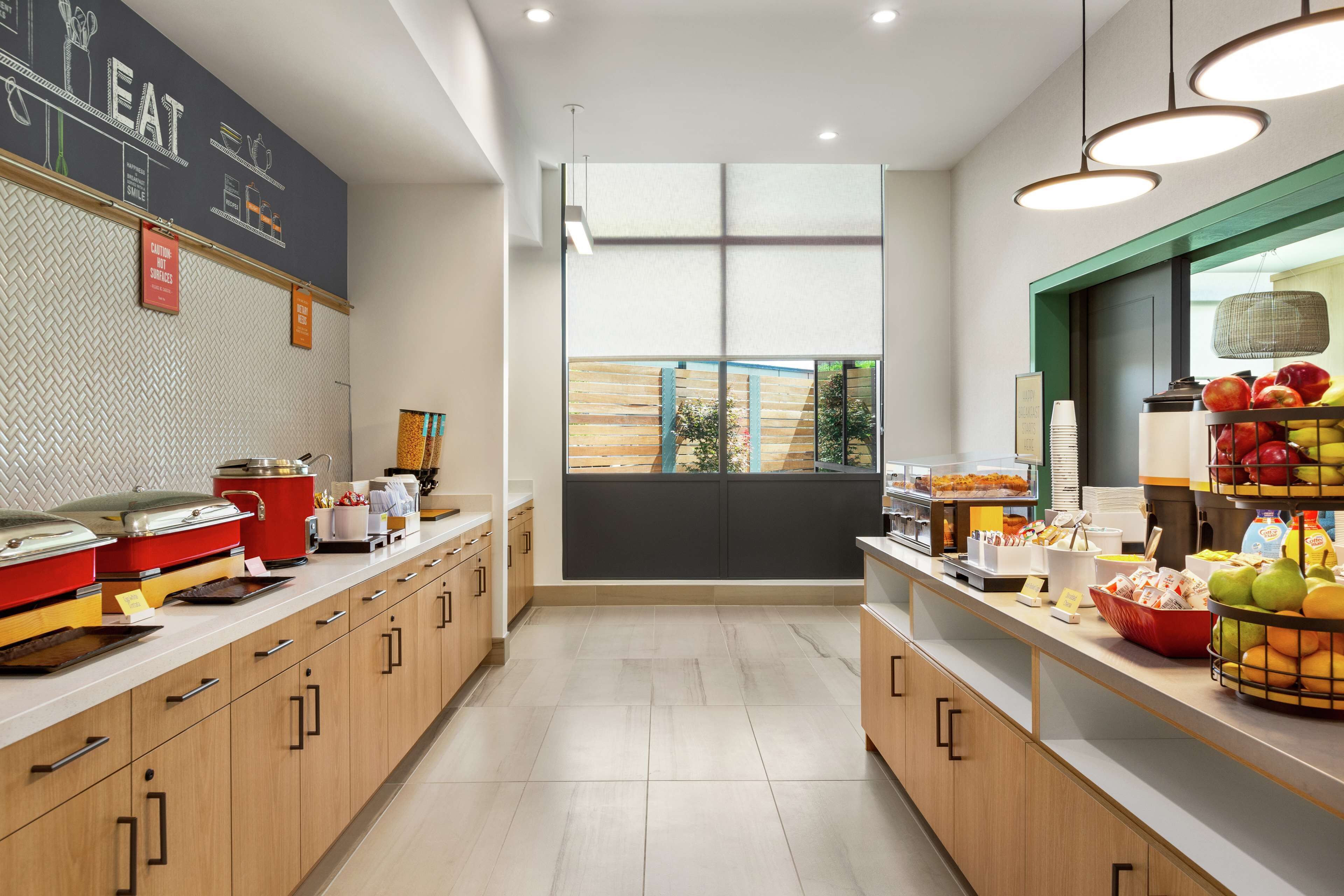 Una cocina moderna con armarios de madera, pared con pizarra y vistas a través de un amplio ventanal.
