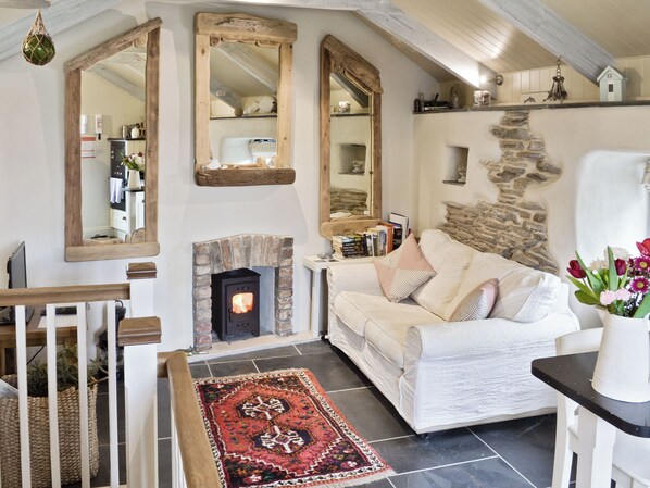 Una sala de estar acogedora con chimenea, un sofá blanco, una alfombra y una pared de piedra.