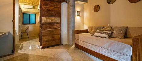 A bedroom with a wooden bed, a sliding door, a small chair, and a wall-mounted light fixture.