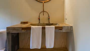 A bathroom with a wooden vanity, a round mirror, and two towels hanging on the sink.
