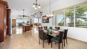 Une cuisine spacieuse avec un coin repas, un ventilateur de plafond et une grande fenêtre donnant sur un paysage verdoyant.