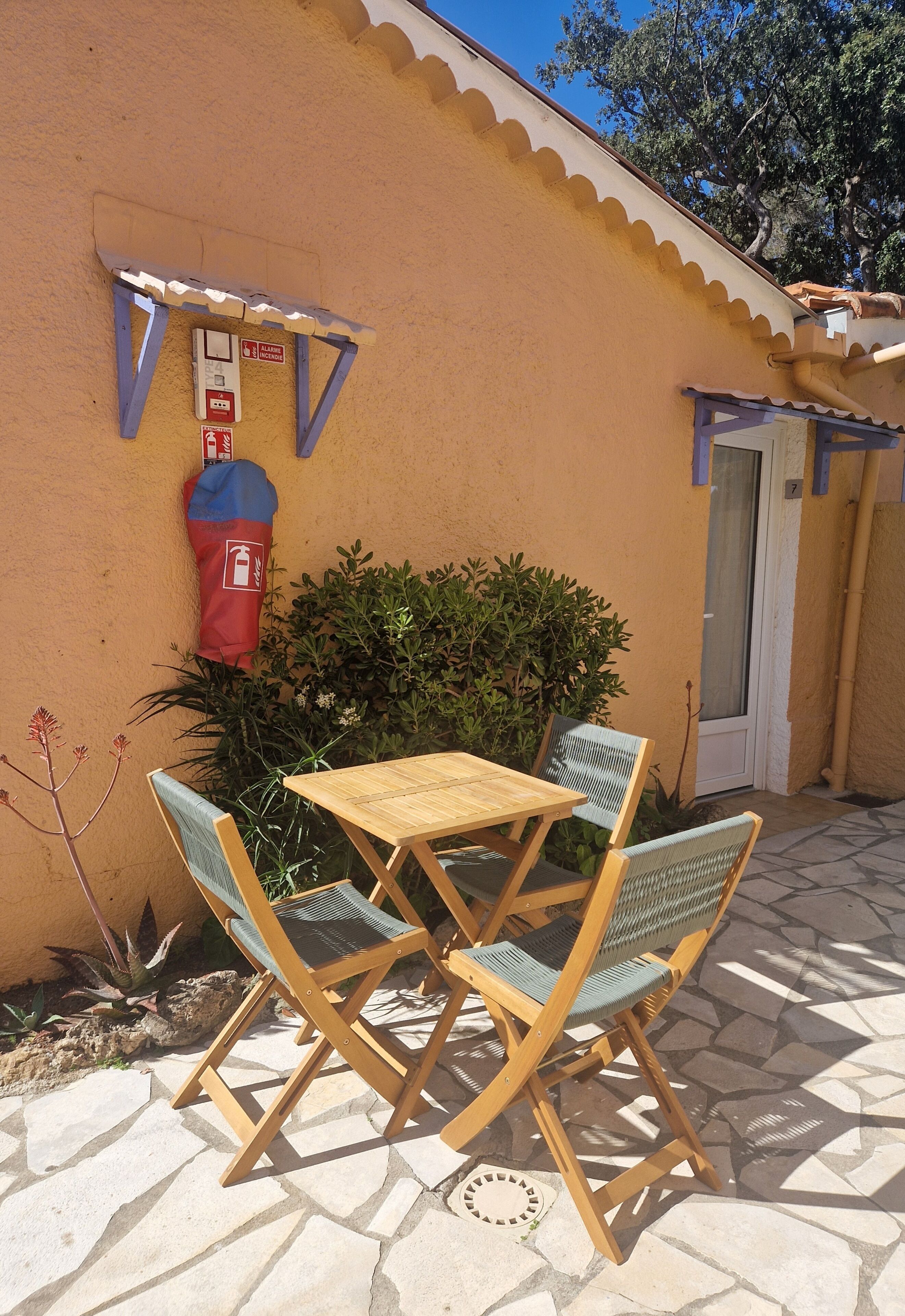 A patio with a table and chairs, a mailbox, and a door.