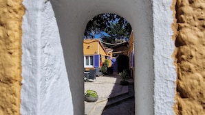 A narrow passageway with a white archway leading to a courtyard with colorful buildings. - le Cosy (Fréjus)