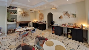 A modern living room with a fireplace, a dining area with a stone floor, and a kitchen area with a bar. - le Cosy (Fréjus)