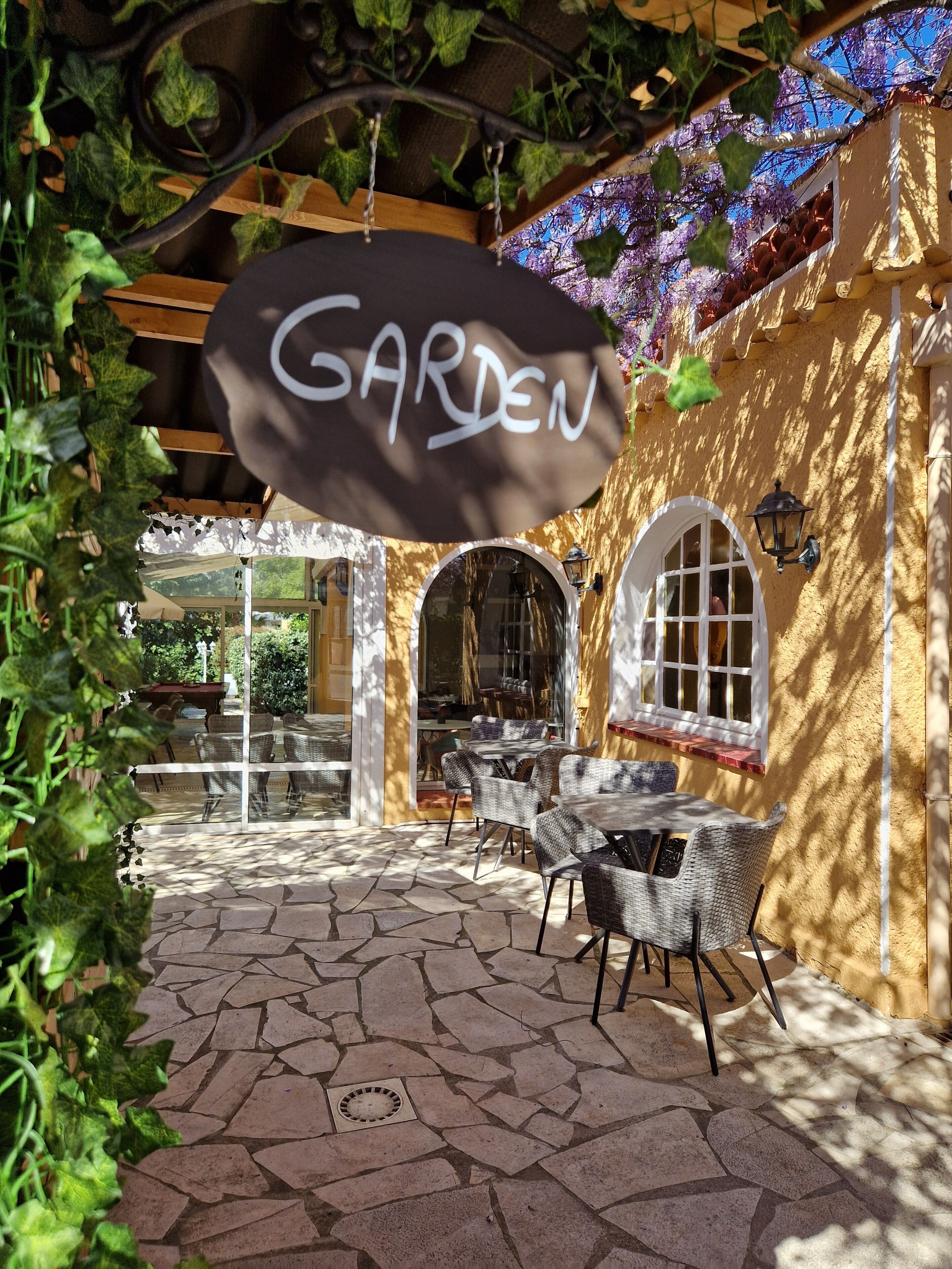 Un patio al aire libre con piso de piedra, muebles de mimbre y un letrero que dice 'GARDEN'.