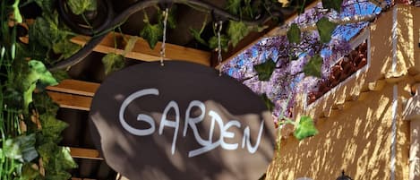 Un patio al aire libre con piso de piedra, muebles de mimbre y un letrero que dice 'GARDEN'.
