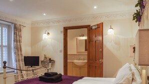 A hotel room with a bed, a wooden door, a bathroom with a sink, and a television on a stand. - 4 bedroom accommodation in Whitby (Whitby)