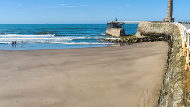 A beach with a lighthouse and a pier. - 4 bedroom accommodation in Whitby (Whitby)