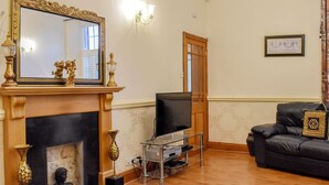 A living room with a fireplace, a television, a sofa, and a framed picture on the wall. - 4 bedroom accommodation in Whitby (Whitby)