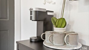 A coffee maker, two mugs, and a potted plant on a table. - Prime Location w King Accommodations Near Downtown (Austin)