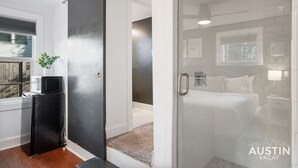A modern hotel room with a glass shower, a bed, and a small kitchenette area. - Prime Location w King Accommodations Near Downtown (Austin)