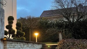 Een stenen trap die naar een gebouw met pannendak leidt, omgeven door bomen en struiken.