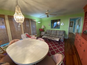 A dining area with a round table and chairs, a sofa, a ceiling fan, and a chandelier.