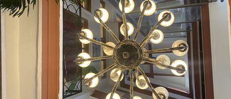 Un candelabro moderno con múltiples bombillas, una ventana que ofrece vistas al exterior y un cuadro en la pared.