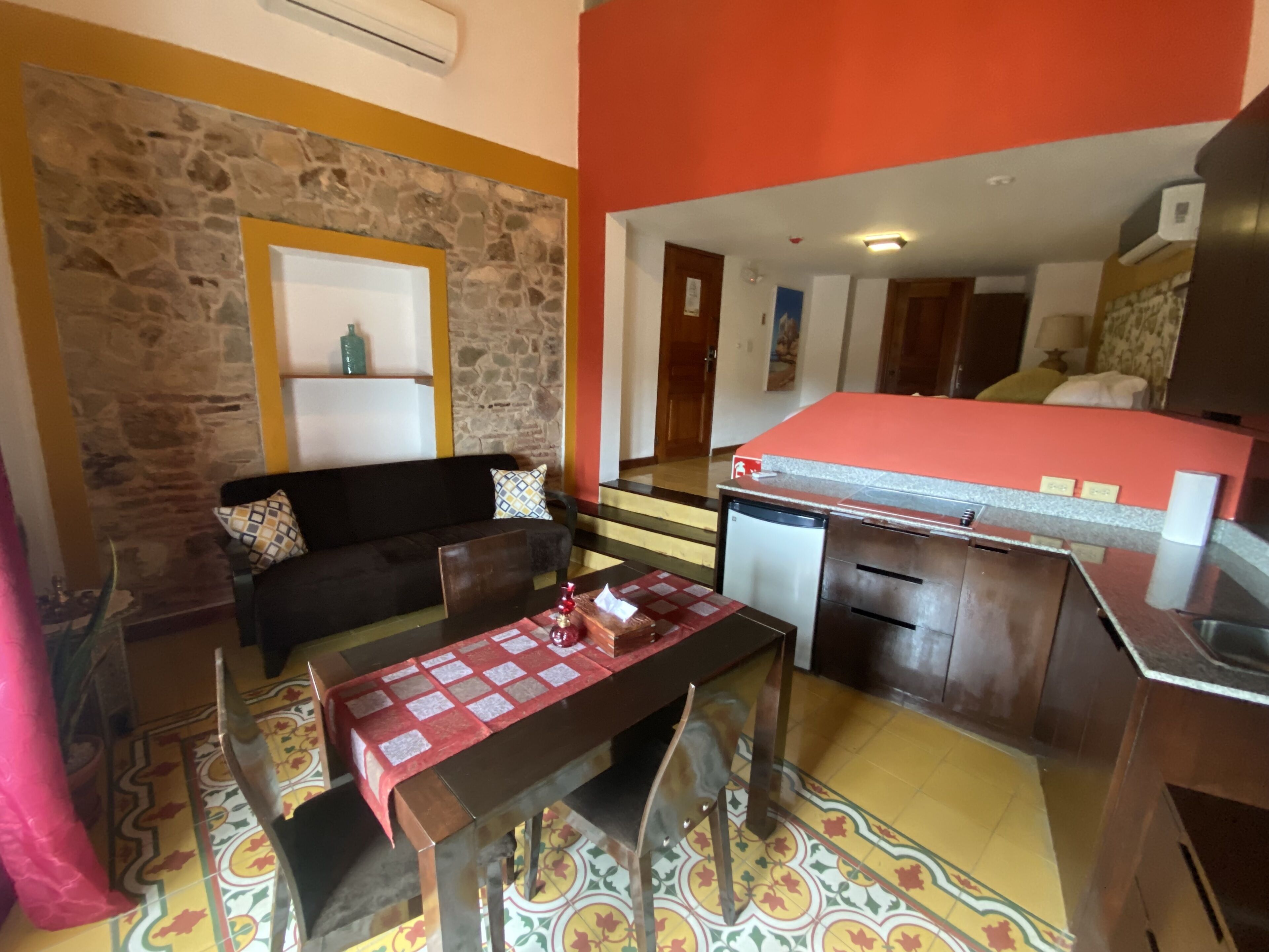 A compact living space with a stone accent wall, a sofa, a dining table, and a kitchenette.