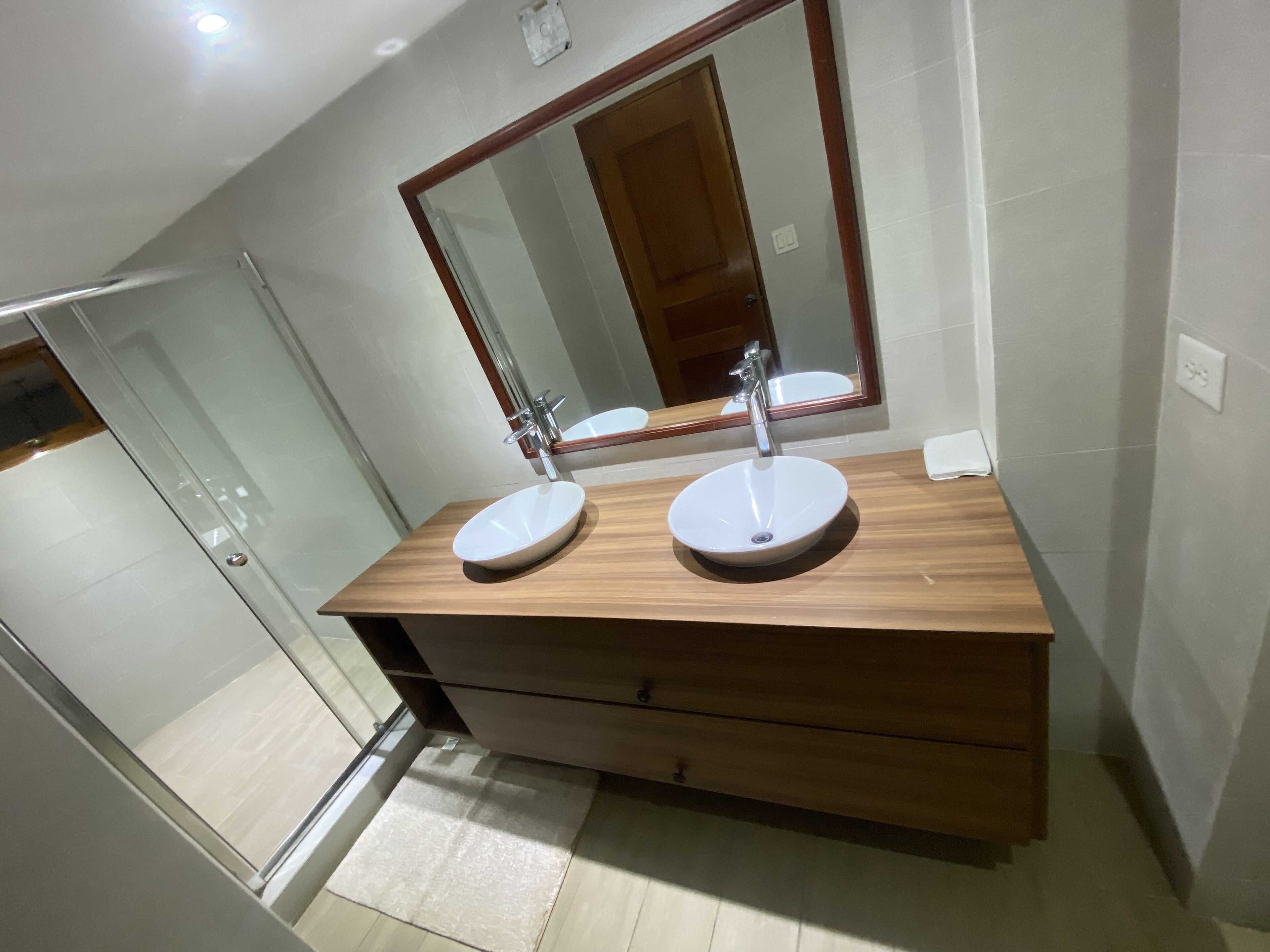 Ein modernes Badezimmer mit zwei Waschbecken, einem großen Spiegel und einem Holzlagerplatz.