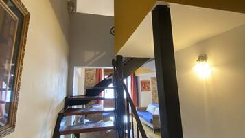Una escalera con peldaños de madera y barandillas negras que sube a un segundo piso.