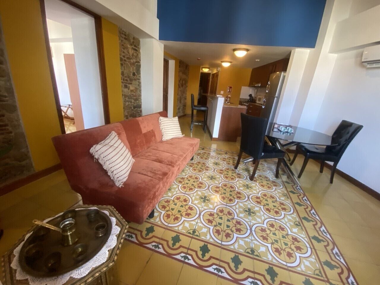A living room with a red sofa, a coffee table, and a patterned floor.