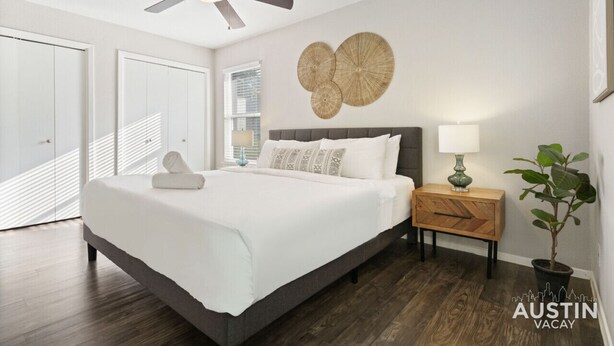 A bedroom with a bed, a ceiling fan, a nightstand with a lamp, a wall art piece, and a potted plant. - Kinney #1 xxxxxxxxxx (Austin)