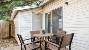 A patio with a round wooden table and four chairs, a sliding glass door, and a laundry room sign. - Kinney #1 xxxxxxxxxx (Austin)