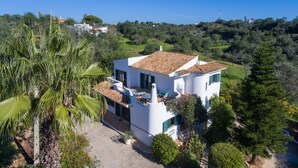 A white villa with a tiled roof, surrounded by lush greenery and a clear sky. - Casa Josephine by Portucasa (Olhao)
