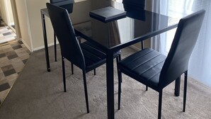A dining area with a glass table and black chairs, a painting on the wall, and a fire extinguisher. - Stunning 2 Bedroom Static Caravan set in 60 Acres (Lincoln)