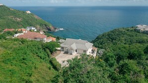 A coastal property with a prominent house surrounded by lush greenery and a view of the ocean. - Uplifting 3 bed beach island cottage (cap estate)