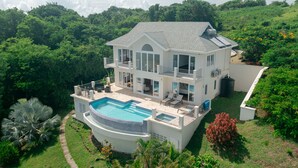 A two-story house with a swimming pool, surrounded by lush greenery. - Uplifting 3 bed beach island cottage (cap estate)