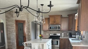 Une cuisine moderne dotée d’un îlot central, d’appareils électroménagers en acier inoxydable et de meubles de rangement en bois.