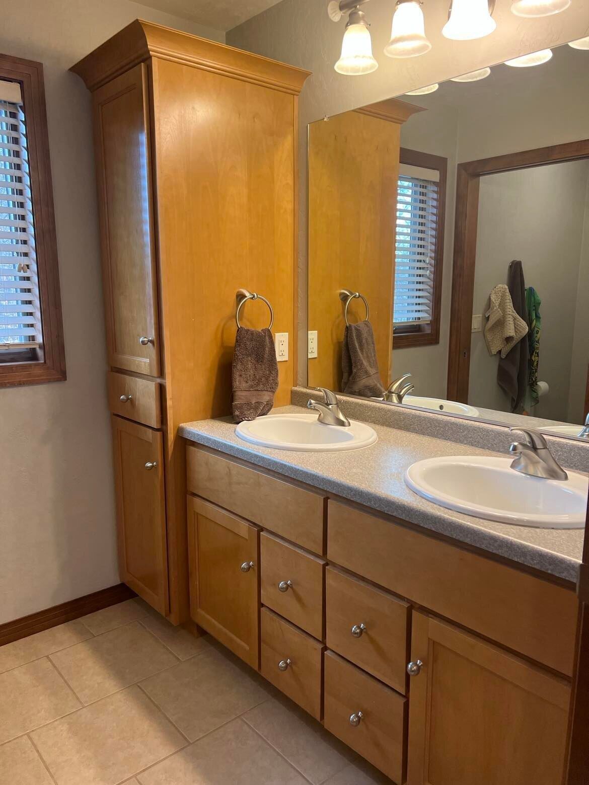 A bathroom with wooden cabinetry, two sinks, and a large mirror.