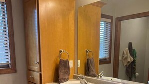 Un baño con muebles de madera, dos lavamanos y un espejo grande.