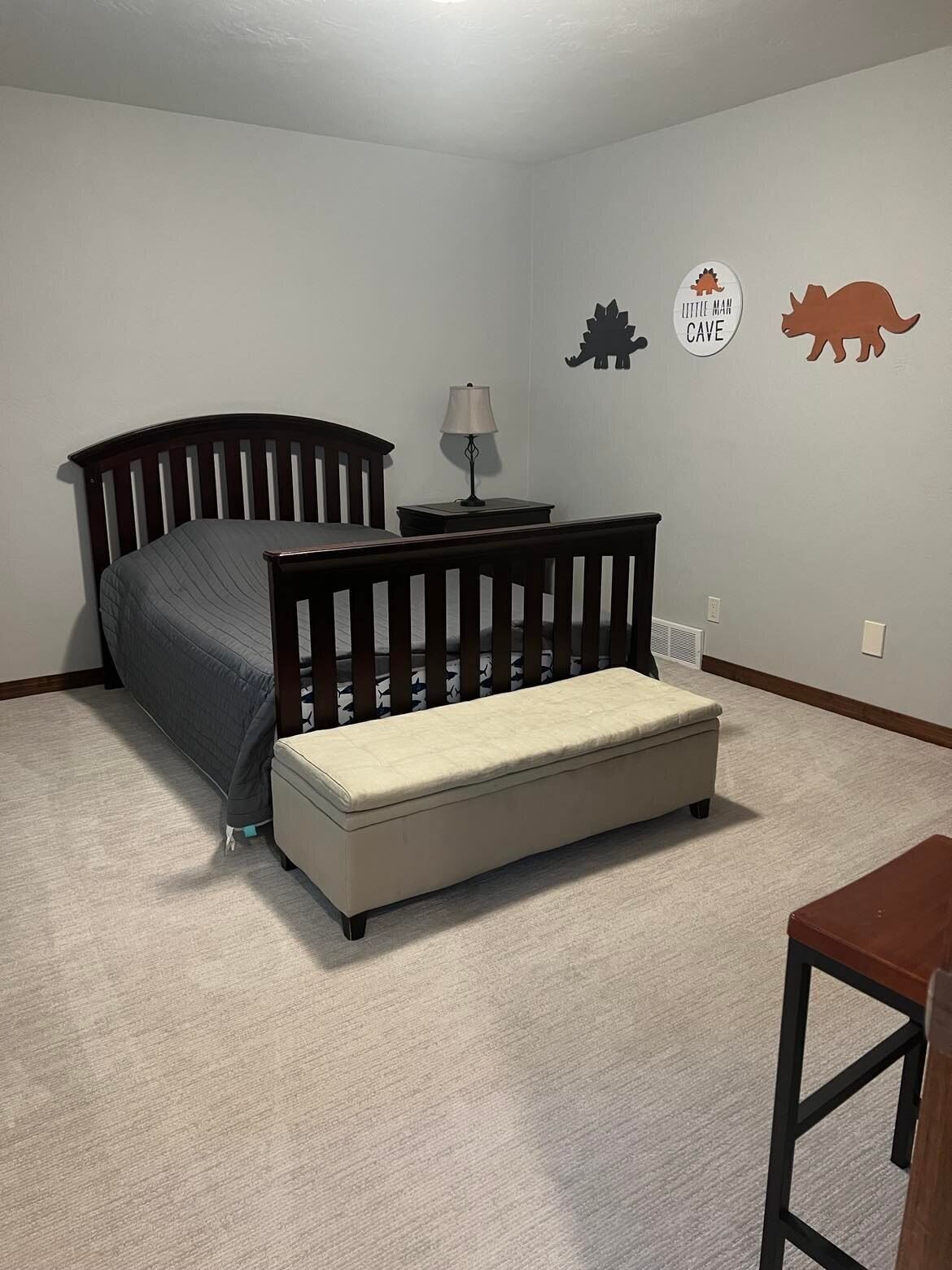 Ein Schlafzimmer mit einem Bett, einem Nachttisch, einer Lampe und einem kleinen Holzsessel.