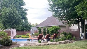 Un patio trasero con piscina, tobogán y mobiliario de exterior.