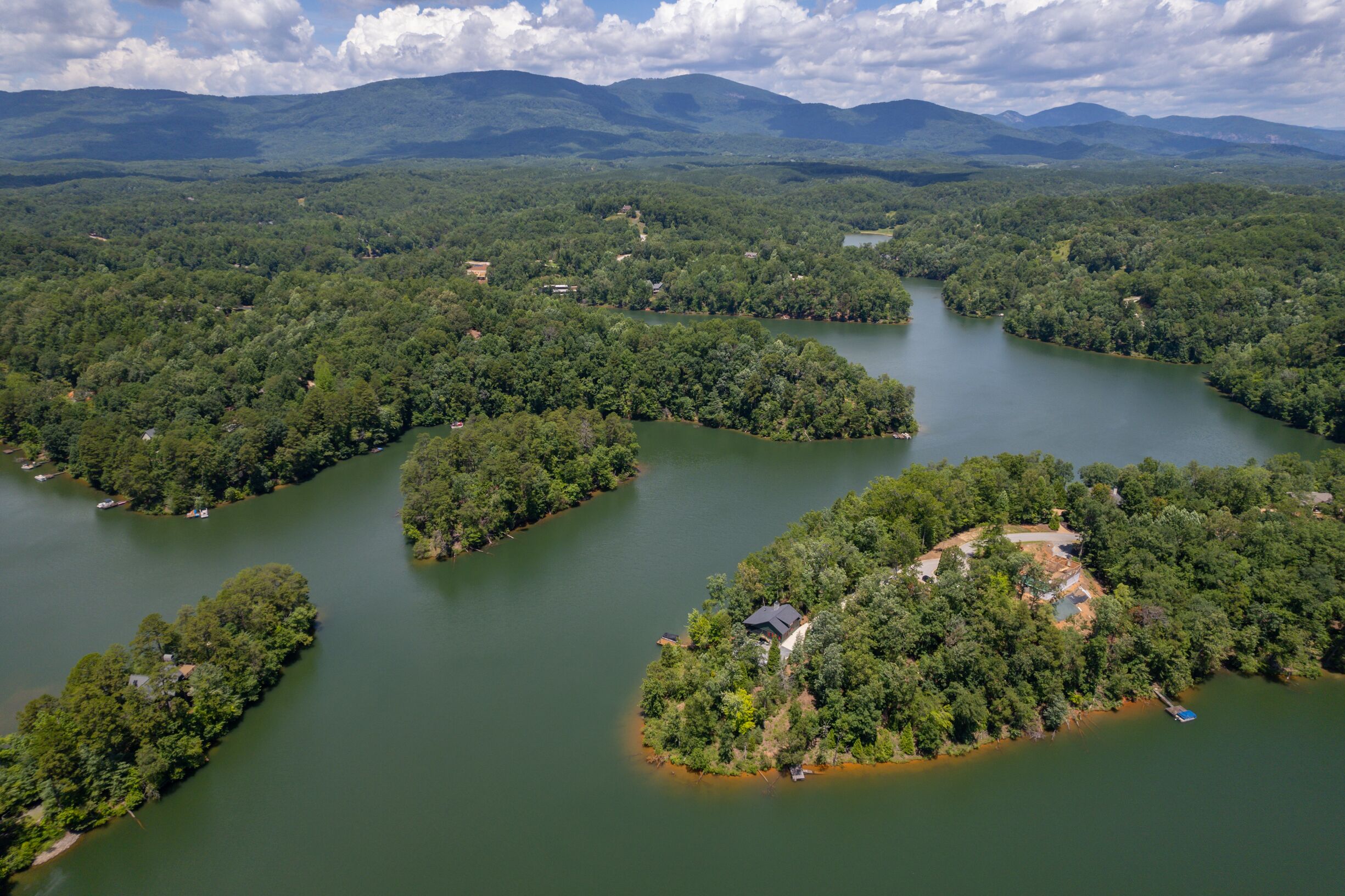 An aerial view of a river with several islands surrounded by dense forests and mountains in the background.
