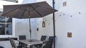 A patio with a table and chairs, a large umbrella, string lights, and decorative wall elements. - 2 bedroom accommodation in Keswick (Keswick)