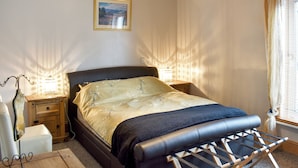 A bedroom with a bed, nightstands, a lamp, a picture on the wall, and a window with curtains. - 2 bedroom accommodation in Keswick (Keswick)