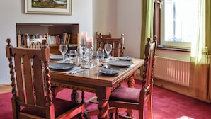 A dining room with a wooden table set for four, surrounded by upholstered chairs. - 2 bedroom accommodation in Keswick (Keswick)