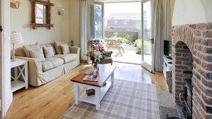 A living room with a sofa, a coffee table, a fireplace, and a view of the backyard.