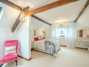 Een slaapkamer met een bed, een kaptafel, een stoel en een kroonluchter.
