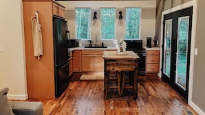 Una cocina compacta con armarios de madera, una isla central y un ventanal con vistas a árboles.