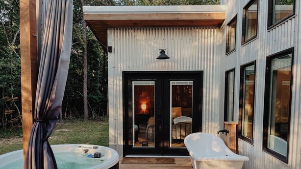 Una casa moderna con un jacuzzi, una terraza de madera y un gran ventanal.