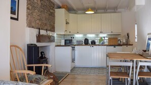 A compact kitchen with white cabinets, a microwave, a kettle, and a toaster. There is a wooden chair and a small table with a laptop. - 2 bedroom accommodation in Crieff (Crieff)